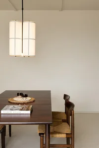 Minimalist dining room with wooden furniture, a wooden dining table with a glass vase and a book, and wooden chairs with wove