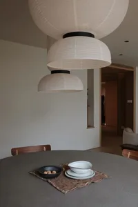 簡約餐廳內，三盞白色紙燈懸掛在圓形餐桌上，桌上擺放黑色碗盛裝核桃