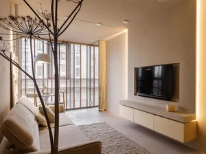 A minimalist living room with concrete flooring, wood furniture, and a floor lamp.