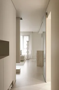 A minimalist white interior space with a light-colored geometric vase and a white sofa.