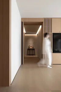 A corridor with modern design features neutral-colored materials, including light-colored wooden panels and flooring, creatin