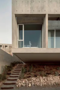 A modern home with a minimalist design featuring concrete and glass materials.