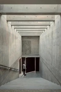 A modern interior space with concrete stairs, minimalist design, and industrial lighting.