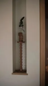 A modern interior design featuring a wooden pedestal with a sculpture displayed on top.