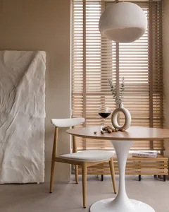 Contemporary dining area featuring a minimalist design with white fabric upholstery and wooden elements, including a round ta