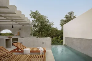A serene modern poolside area with concrete structures and natural surroundings.