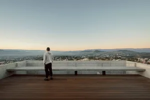 A man standing on a concrete platform overlooking a scenic landscape.