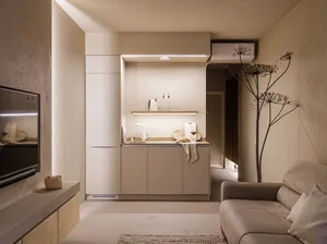 A minimalist residential kitchen with concrete walls and neutral color cabinets.