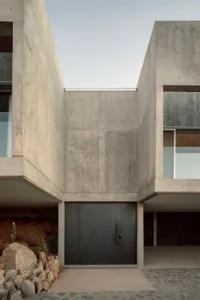 Modern house with concrete exterior and large glass windows.