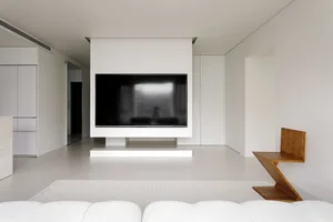 White minimalist living room with concrete flooring and furniture.