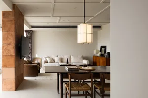 A modern minimalist living room featuring wooden furniture, white walls, and a white sofa with white cushions.
