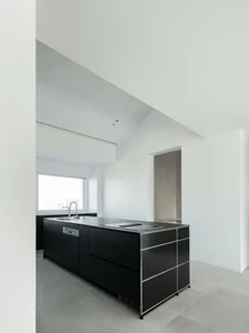 Modern kitchen with black cabinets and concrete countertops.