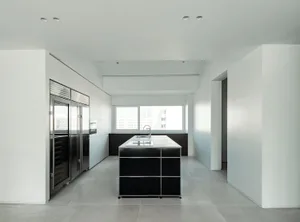 A modern kitchen with black metal cabinets and a concrete floor.