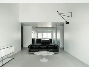 A minimalist living room with a black leather couch, white marble coffee table, and sleek, metallic furnishings.
