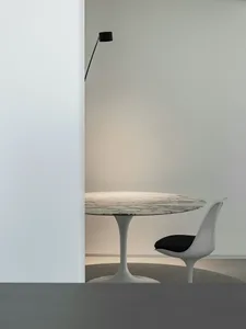 A minimalist modern dining room featuring a round marble table with a sleek, white tulip base and a single white chair with a