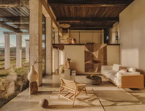 A minimalist living room featuring concrete, wooden elements, and woven furnishings.