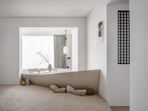 Minimalist living room with white walls, a sleek white bench, and natural stone accents.