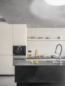 A minimalist residential kitchen with a sleek, industrial concrete countertop, featuring stainless steel appliances and a mod