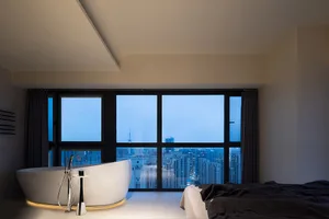 Modern bathroom featuring a large free-standing bathtub with a cityscape view through the floor-to-ceiling windows.