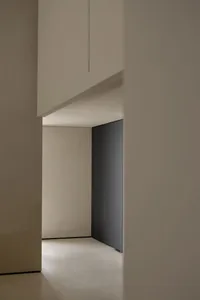 Modern residential interior with concrete walls and floor, minimal furniture.