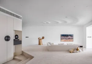 A modern living room with concrete furniture, a white couch, and a unique art piece on the wall.