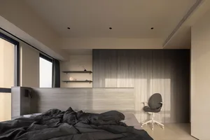 A modern minimalist bedroom with a grey bedspread and wooden shelves.