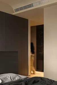 A modern minimalist bedroom featuring dark wood cabinets and warm lighting.