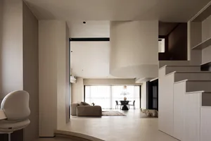 A modern minimalist living and dining space featuring neutral-toned materials and a mix of materials.