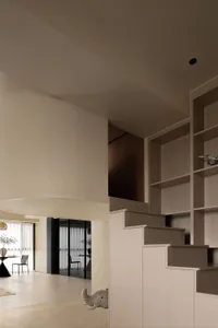 A modern living room with neutral-toned wall paneling, open space, and minimalist decor.