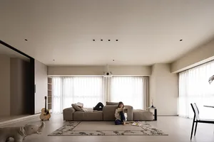 A modern living room with neutral-toned furniture, large windows, and a cozy atmosphere.