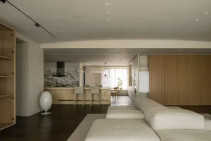 Modern residential kitchen with marble countertops, wood walls, and glass pendant lights.