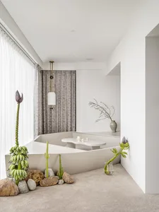 A minimalist bathroom with concrete elements, including a bathtub, table, and surrounding rocks and plants.