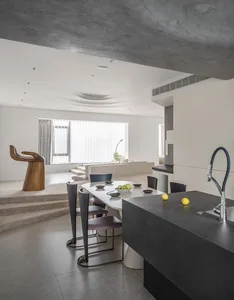 A modern living room with concrete walls, wooden furniture, and minimalist decor.