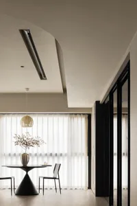 A minimalist modern residential living space featuring transparent textiles and dark wooden accents.