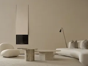 A minimalist living room with stone coffee tables and a curved fabric sofa, accentuated with soft lighting.