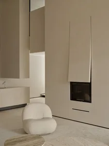 A minimalist living room with concrete walls and floor, featuring a curved white chair and a round wooden coffee table.