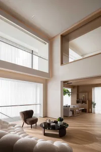 Modern minimalist living room with wood accents, featuring a large sofa, armchair, and coffee table.
