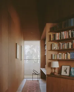 A minimalist home library featuring a wooden wall and shelves filled with books.
