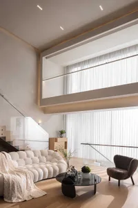 A modern living room featuring a white sofa and wooden floors, with large windows allowing natural light to flood the space.