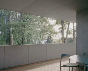 Minimalist balcony with wooden flooring and a view of trees through a glass wall