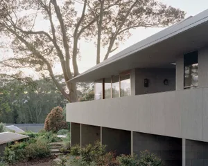 A modern residential exterior featuring metal cladding under a tree.