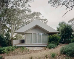 A minimalist residential house with a concrete exterior and large windows.