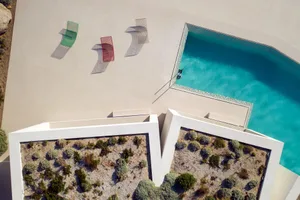 An aerial view of a modern pool deck with concrete materials and colorful outdoor furniture.