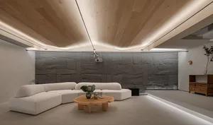 A minimalist living room with a curved white sofa and a round wooden table.