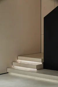 A minimalist marble staircase with embedded lighting against a neutral wall.