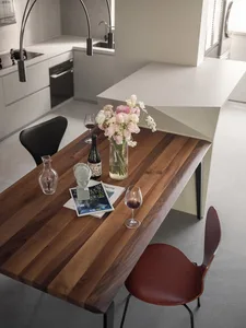 A modern dining room with a wooden table, metal chairs, and decorative elements including a vase of flowers, a bottle, and ma