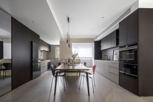 Modern kitchen with wooden countertops and table, featuring stainless steel appliances and a large window.