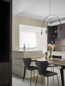 Modern kitchen with wooden table, black chairs, and a vase of flowers.