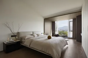 A modern minimalist bedroom featuring a wood floor, large window with mountain view, and simple furniture.