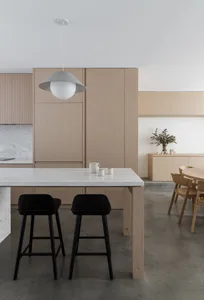 Modern minimalist kitchen featuring wood cabinets, a marble countertop, and concrete flooring.